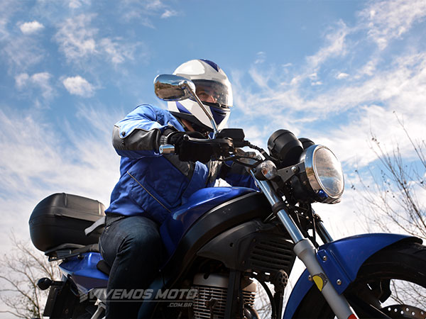 Motociclista ou Motoboy pilotando a moto com capacete, luvas e jaqueta.